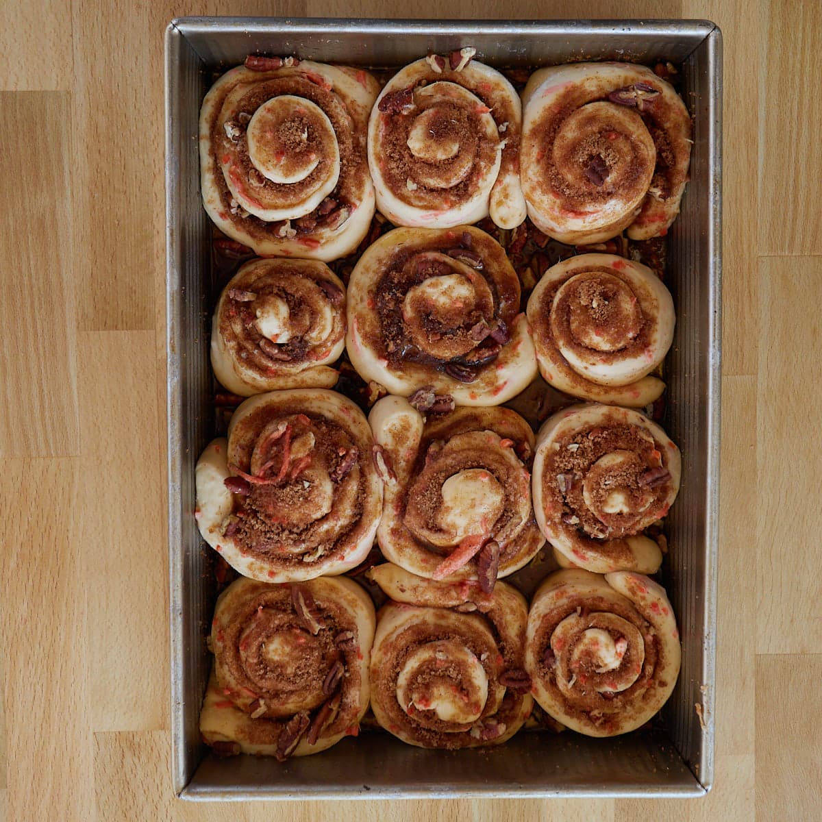 12 rolled up carrot cake sourdough cinnamon rolls in a greased 9x13 inch pan after the second rise. 