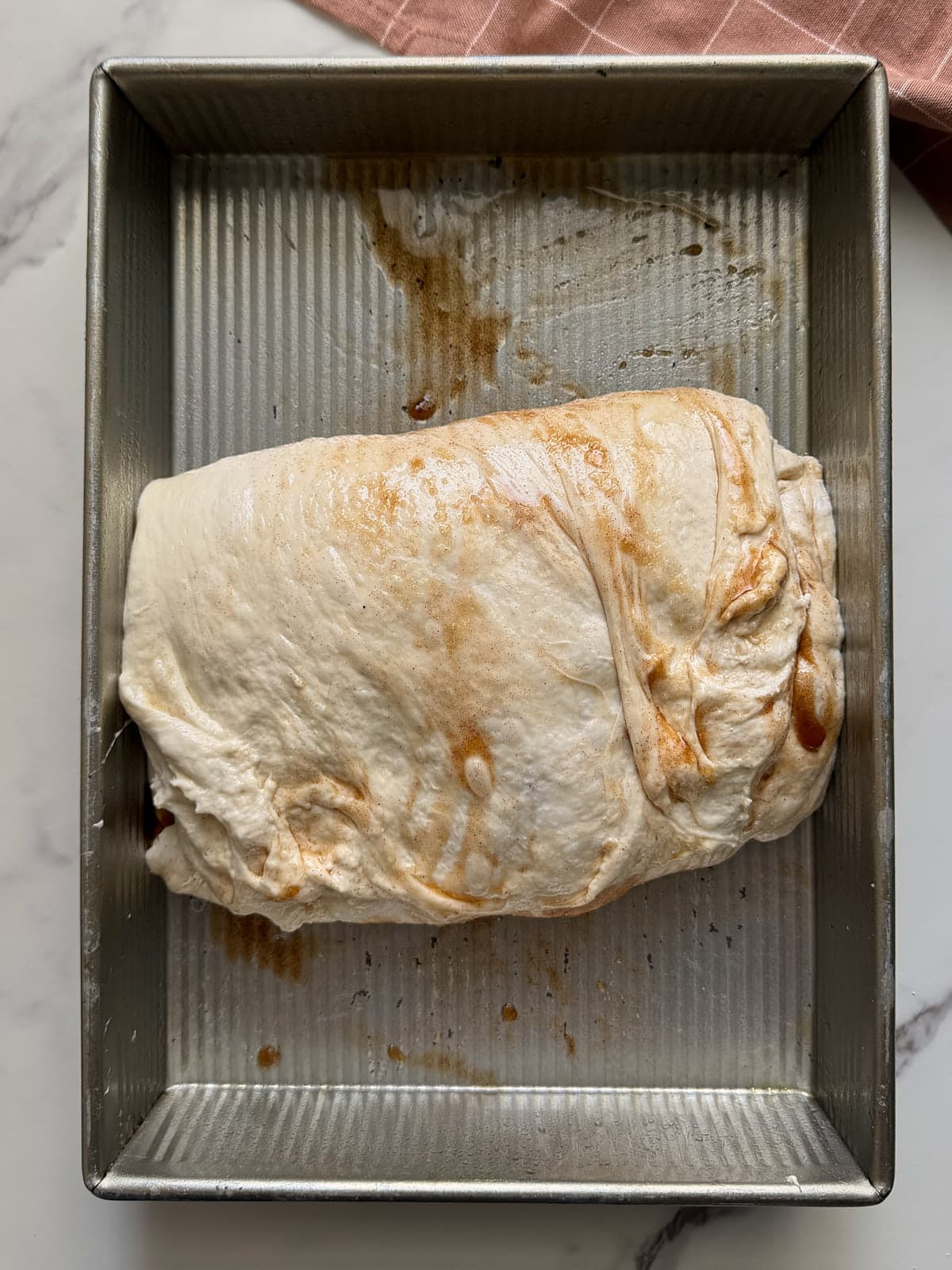 Folded sourdough cinnamon sugar focaccia dough in a metal 9x13 pan.