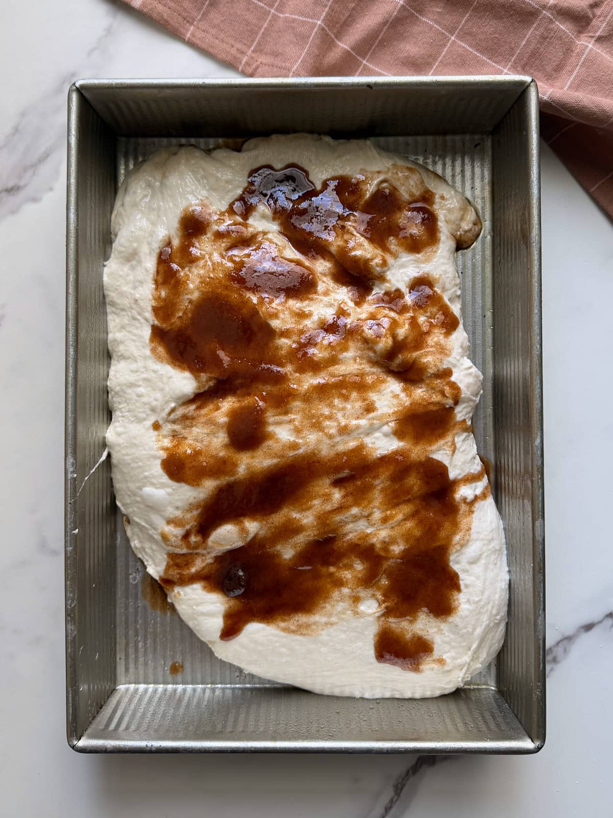 Sourdough cinnamon roll dough in a 9x13 pan with cinnamon sugar on top. 