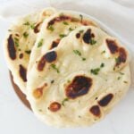 three sourdough naan bread stacked on top of each other with a garlic herb butter