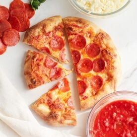 Three slices of sourdough pepperoni pizza next to the full pizza.