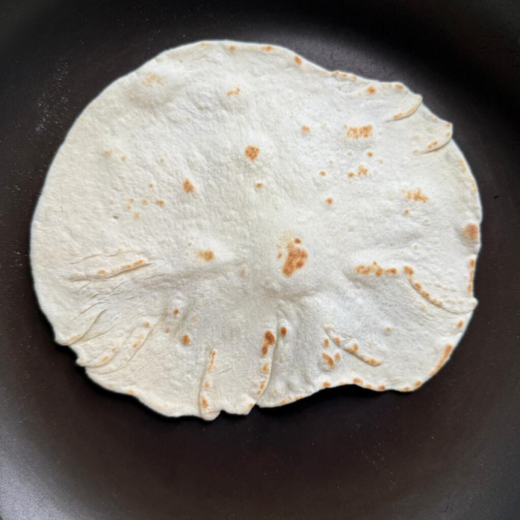 sourdough flour tortilla in a non-stick pan after being flipped once.