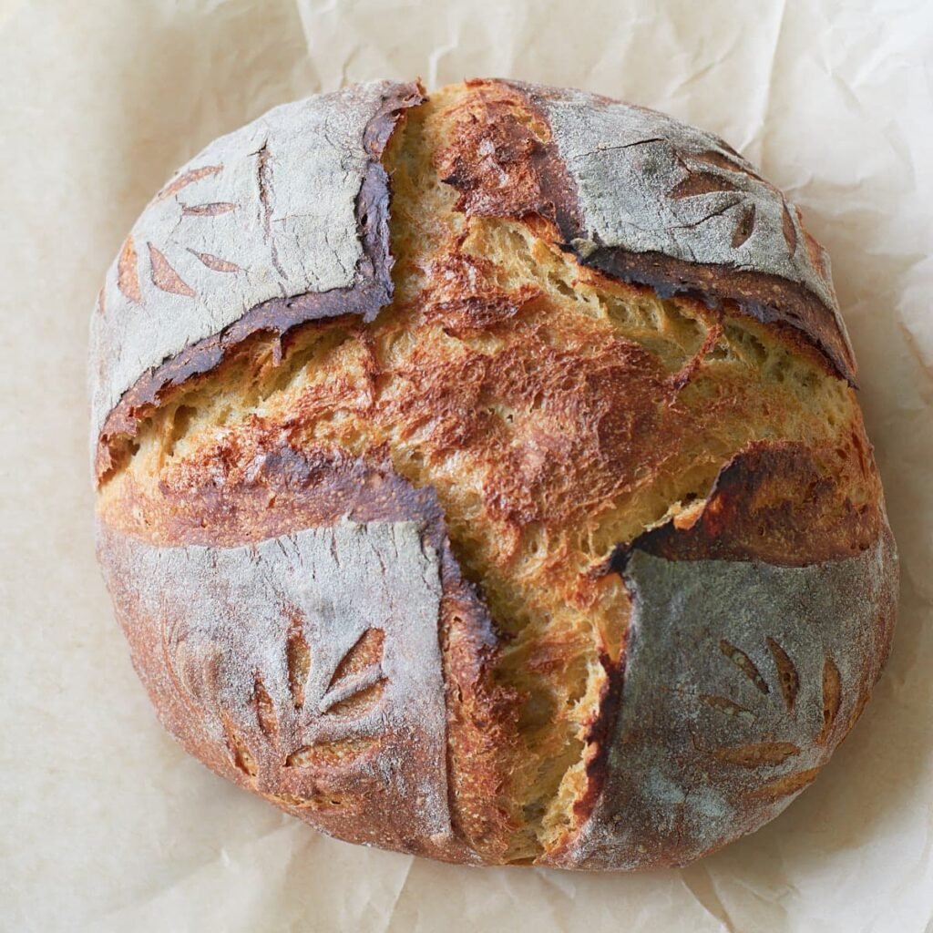 Freshly baked Einkorn Sourdough Bread on top of a piece of brown parchment paper.