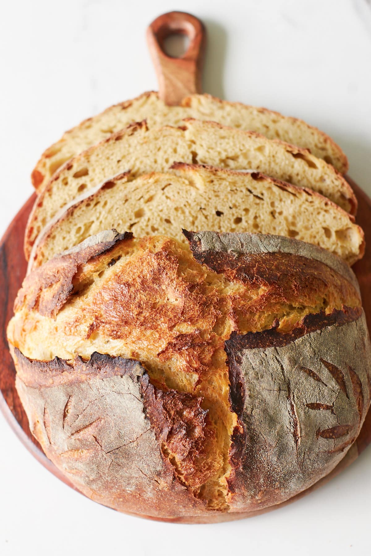 Loaf of Einkorn Sourdough Bread with three slices on top of a wooden board.