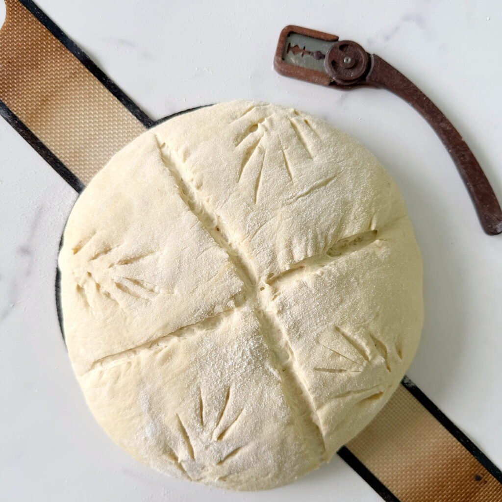 Dough with an "X" scored on top with small wheat stalks.