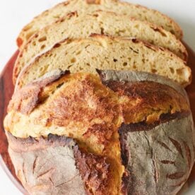 Loaf of Einkorn Sourdough Bread with three slices on top of a wooden board.