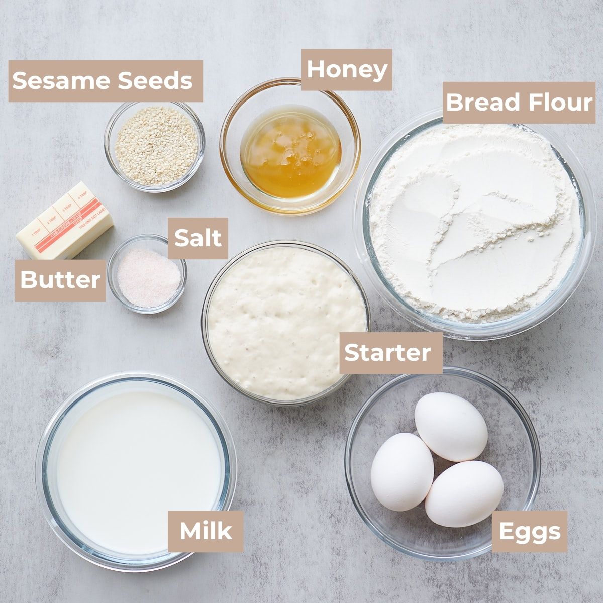 Ingredients for Sourdough Hamburger Buns in clear bowls.