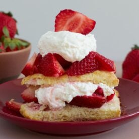 Sourdough Strawberry Shortcake with layers of whipped cream on a red plate.