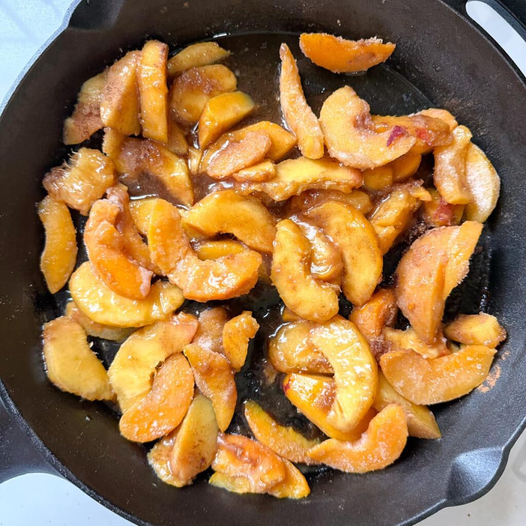 Peaches with cinnamon and brown sugar in cast iron pan.