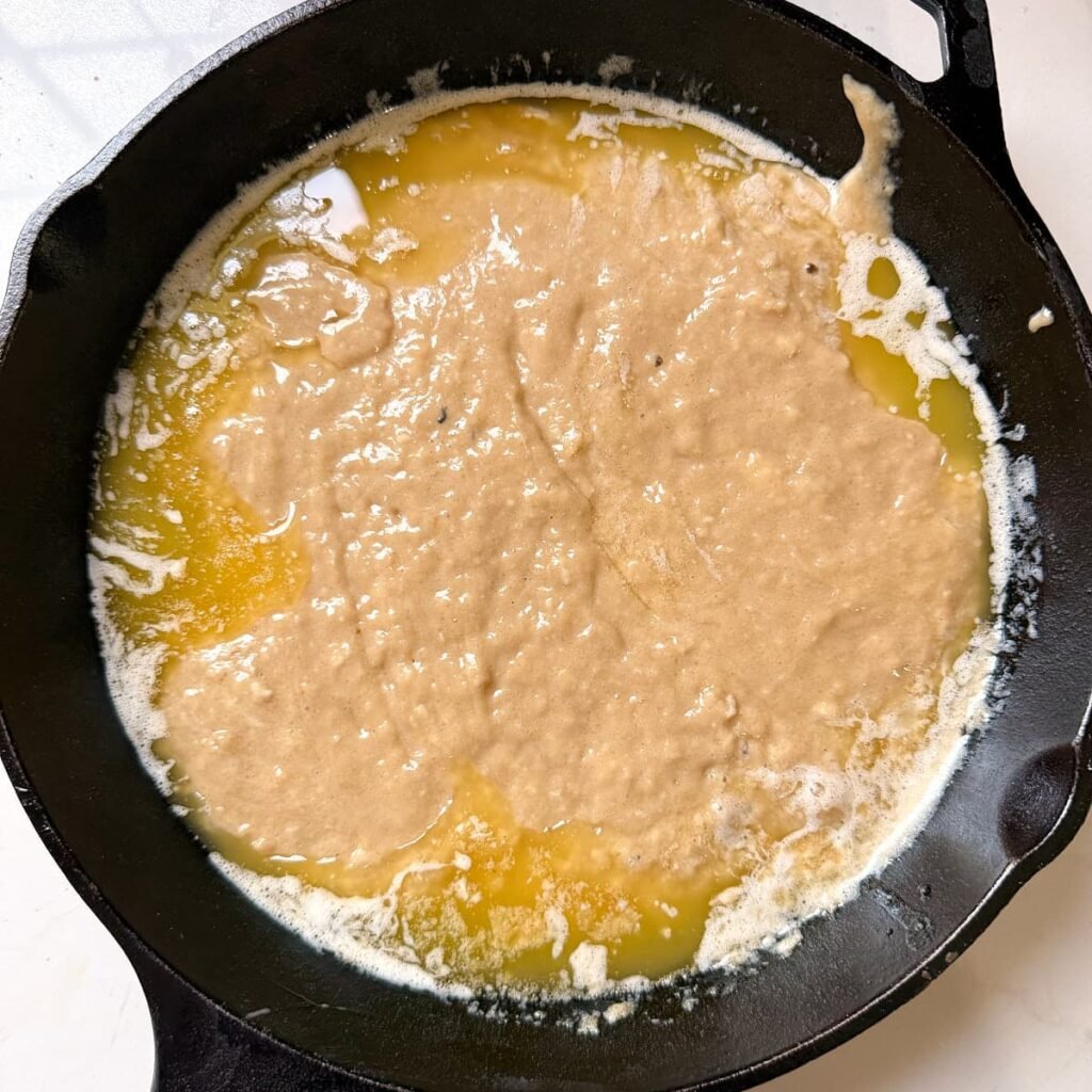 Cobbler batter added to butter in a hot cast iron pan.