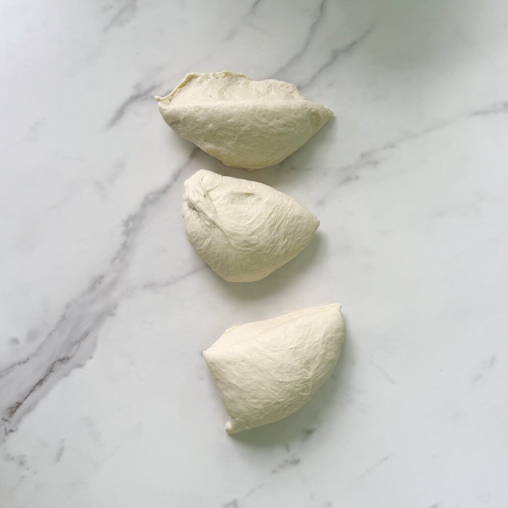 Sourdough pretzel dough cut into three pieces.