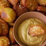 Sourdough Pretzel Bites with a small bowl of mustard and one pretzel bite dipped inside.
