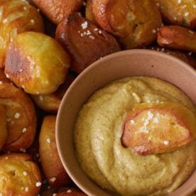 Sourdough Pretzel Bites with a small bowl of mustard and one pretzel bite dipped inside.
