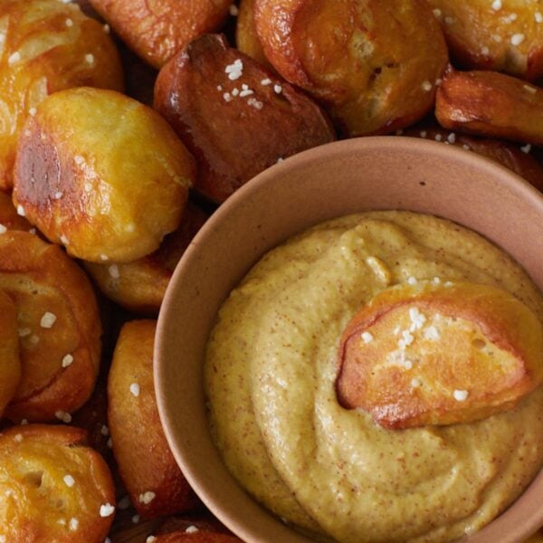 Sourdough Pretzel Bites with a small bowl of mustard and one pretzel bite dipped inside.