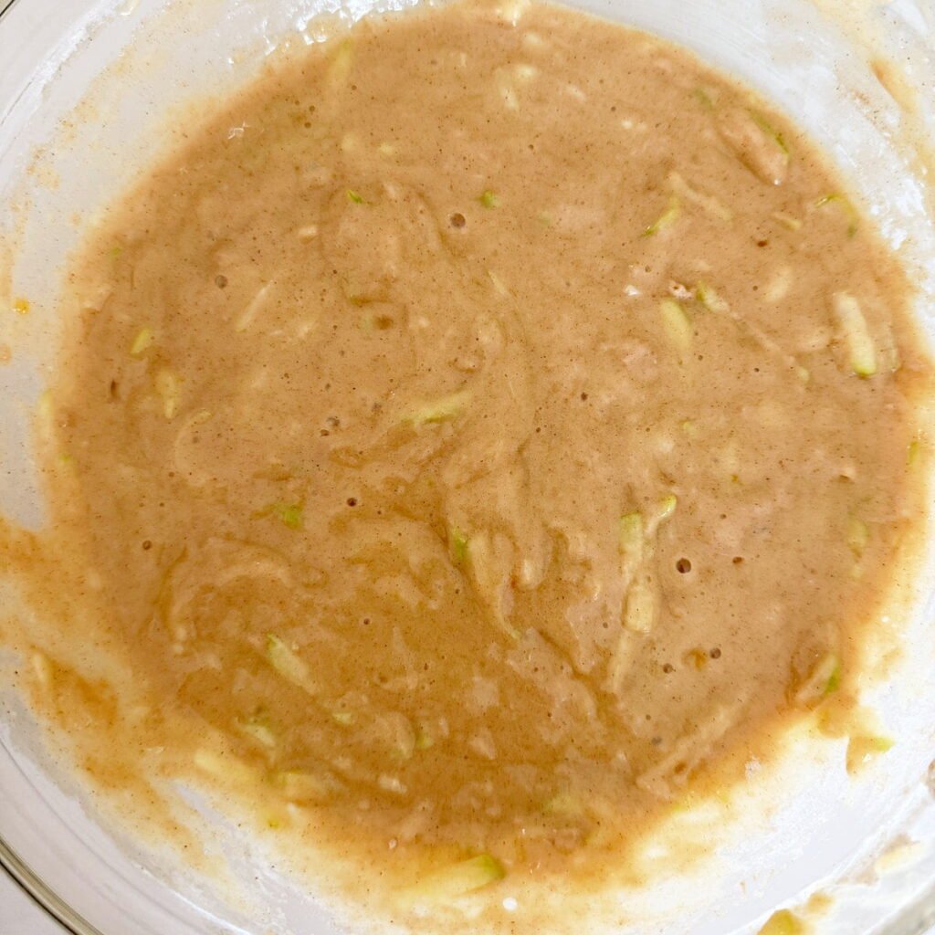 Batter for sourdough zucchini bread in a clear bowl.