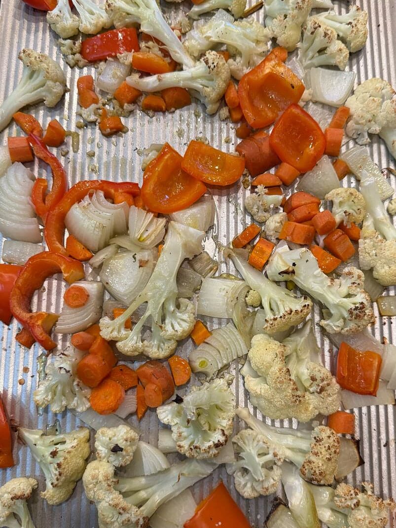 roasted carrots, red pepper, cauliflower, and onion diced and on a sheet pan.