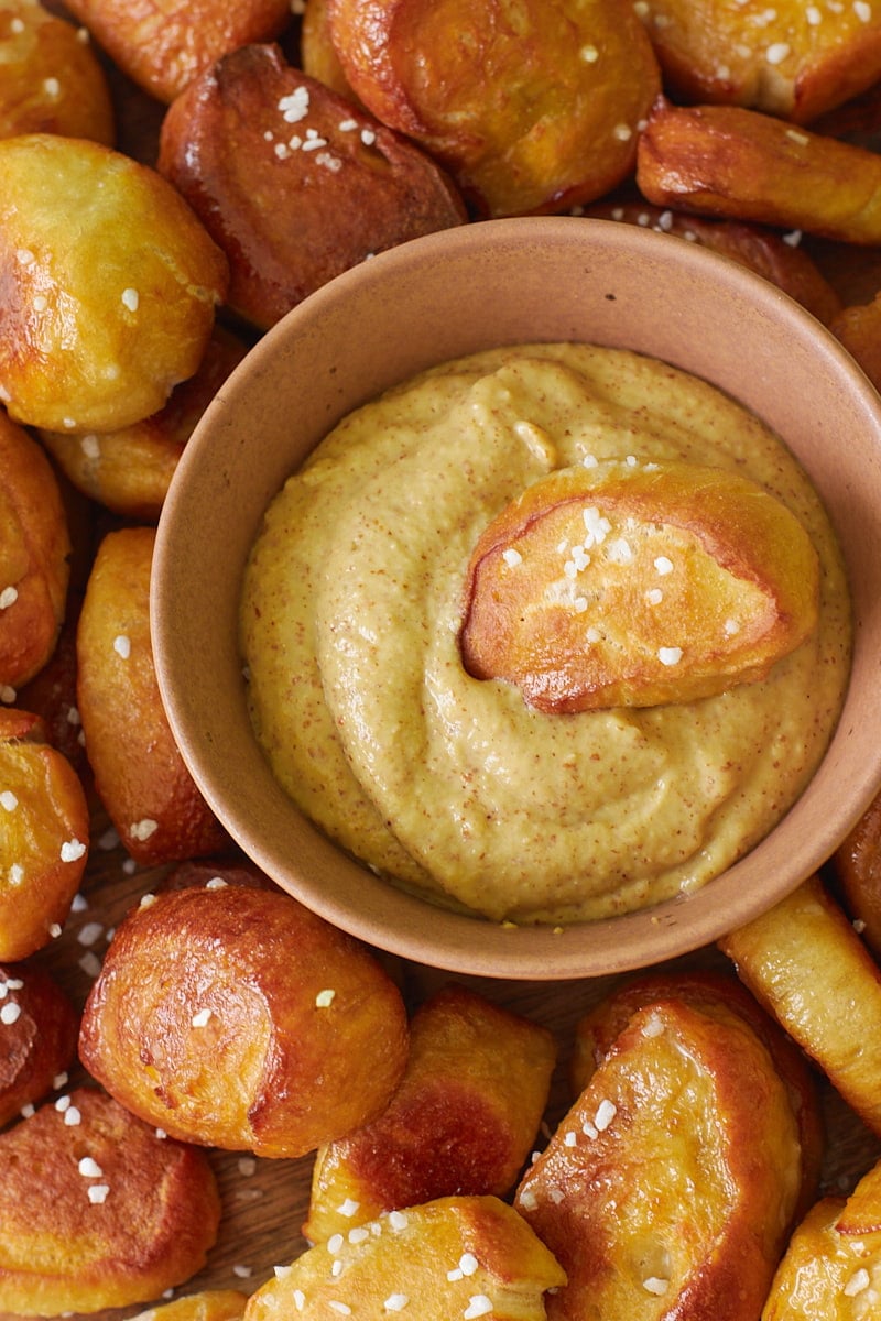 Sourdough Pretzel Bites with a small bowl of mustard and one pretzel bite dipped inside.