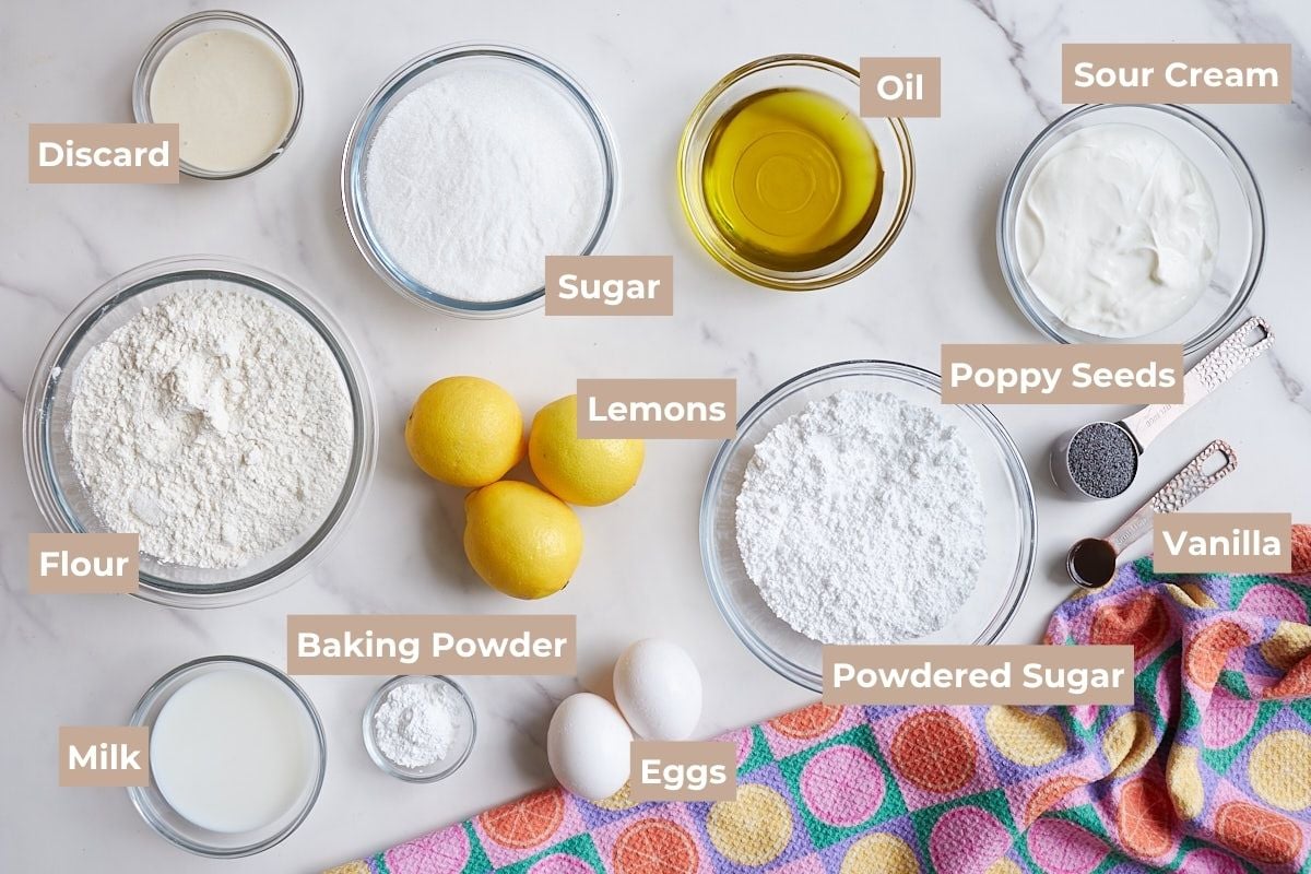 Ingredients for Lemon Poppyseed Sourdough Muffins on a white background with a lemon printed towel.