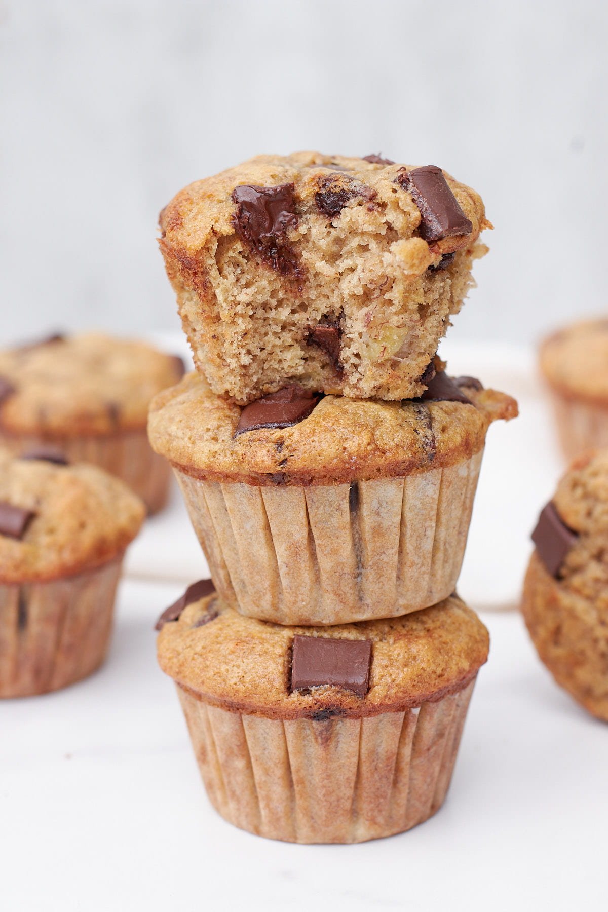 Three Sourdough Banana Muffins stacked on top of each other with a bite taken out of the top one.