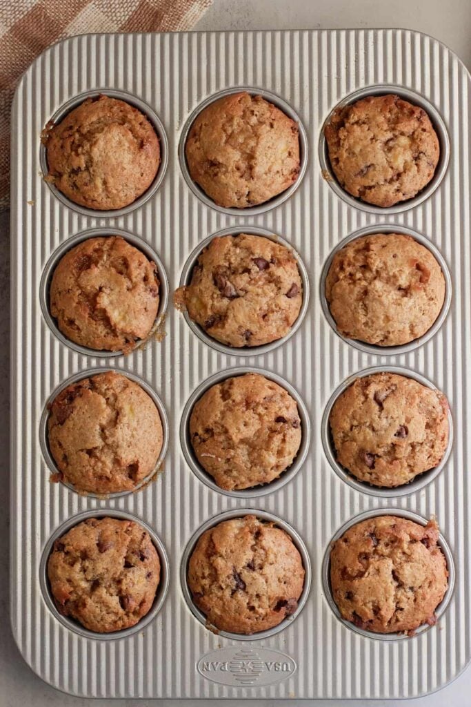 Freshly baked sourdough banana muffins in a muffin pan.