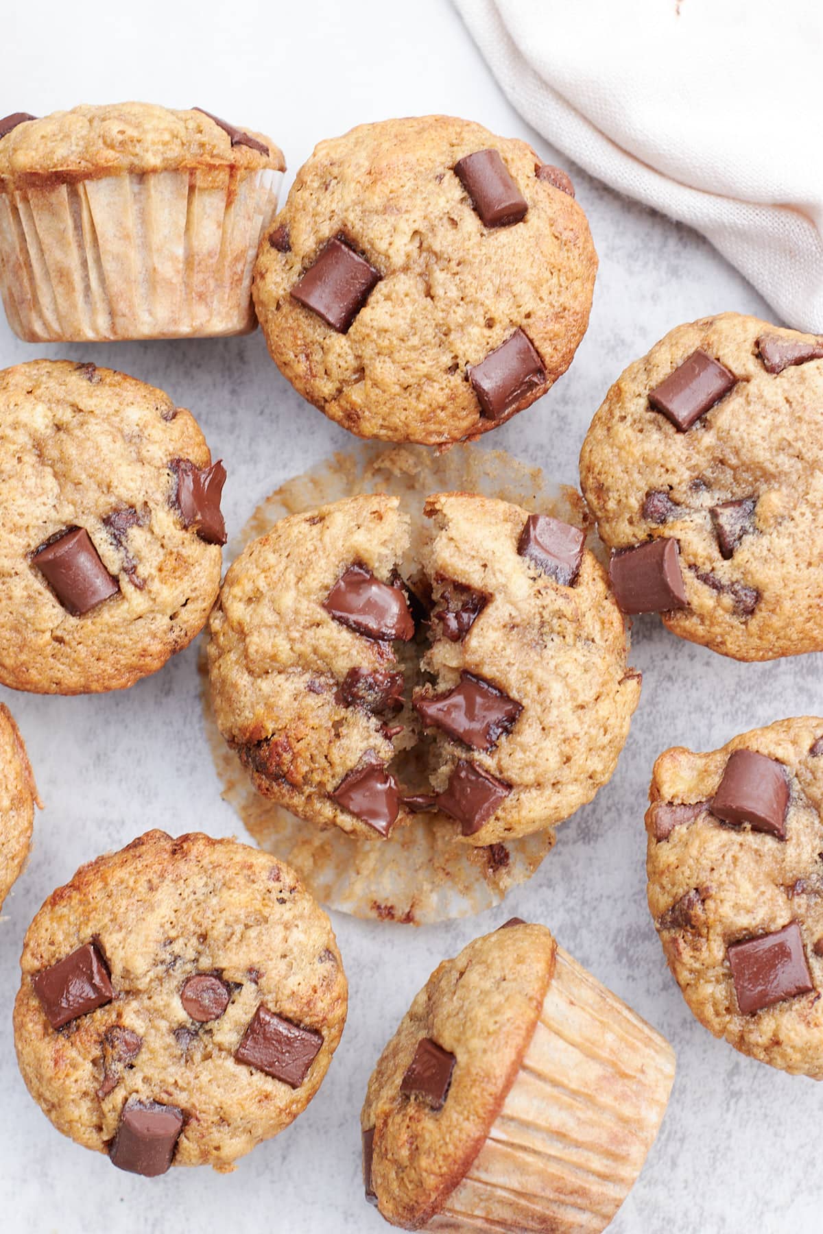 Sourdough Banana Muffins with Chocolate chips on a grey background with one cut in half.