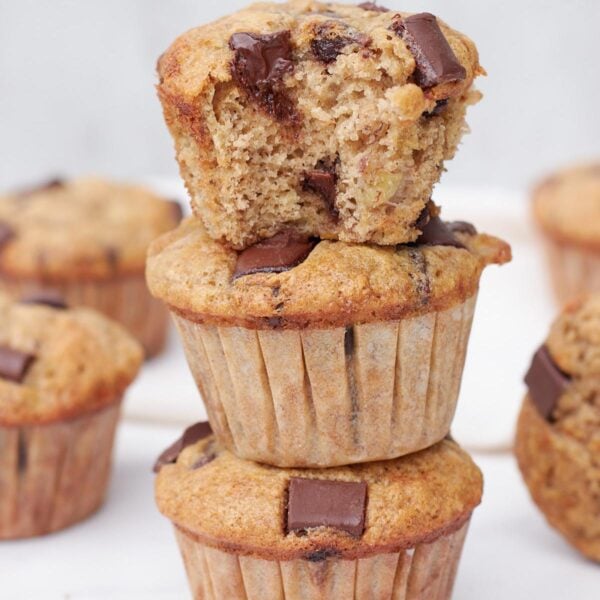 Three Sourdough Banana Muffins stacked on top of each other with a bite taken out of the top one.