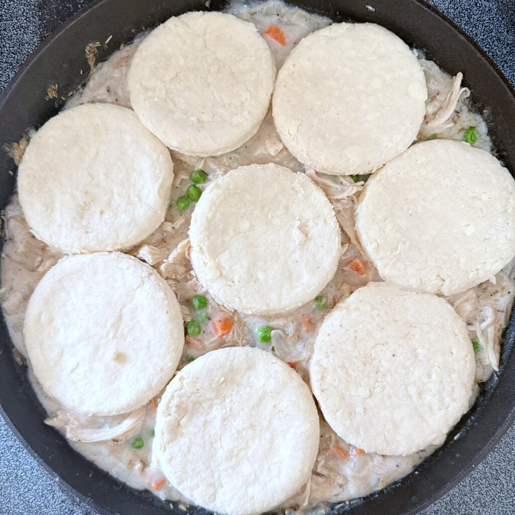 Sourdough biscuits added on top of chicken pot pie base in cast iron skillet.
