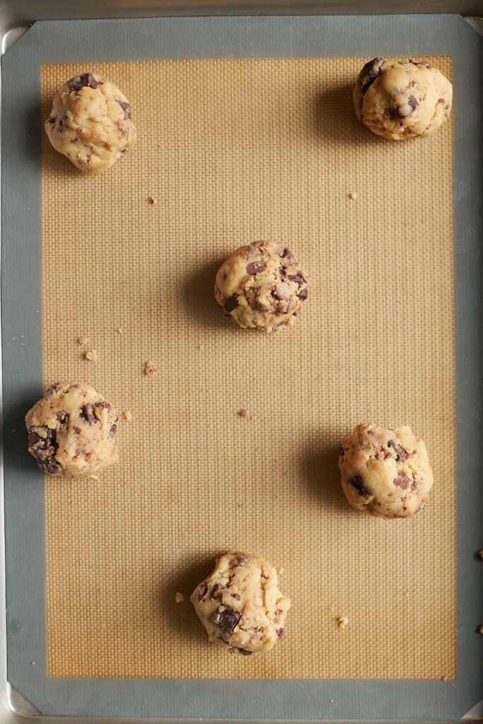 6 Sourdough Chocolate Chip Cookie dough balls on a sheet pan.