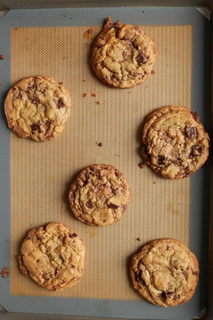 6 freshly baked Sourdough Chocolate Chip Cookies on a sheet pan.