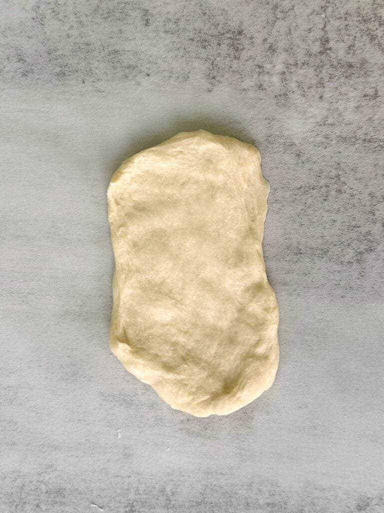 Dough for sourdough hot dog buns rolled in a 4x6 rectangle.