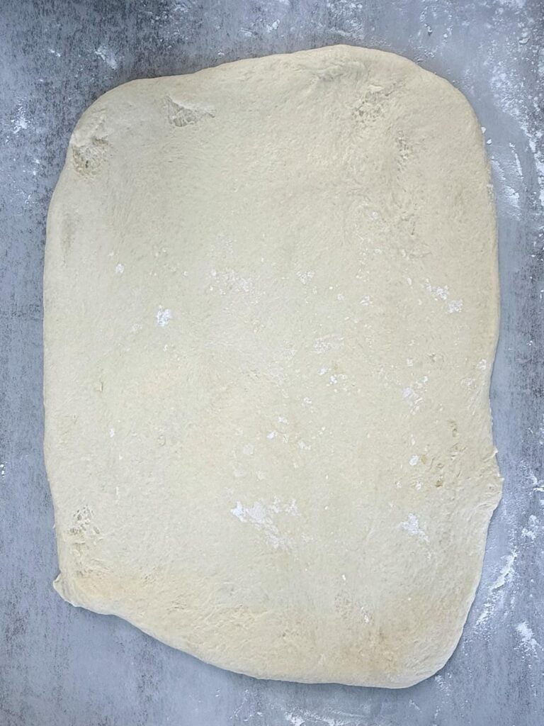 Dough for Sourdough Peach Cobbler Cinnamon Rolls rolled out into a rectangle.