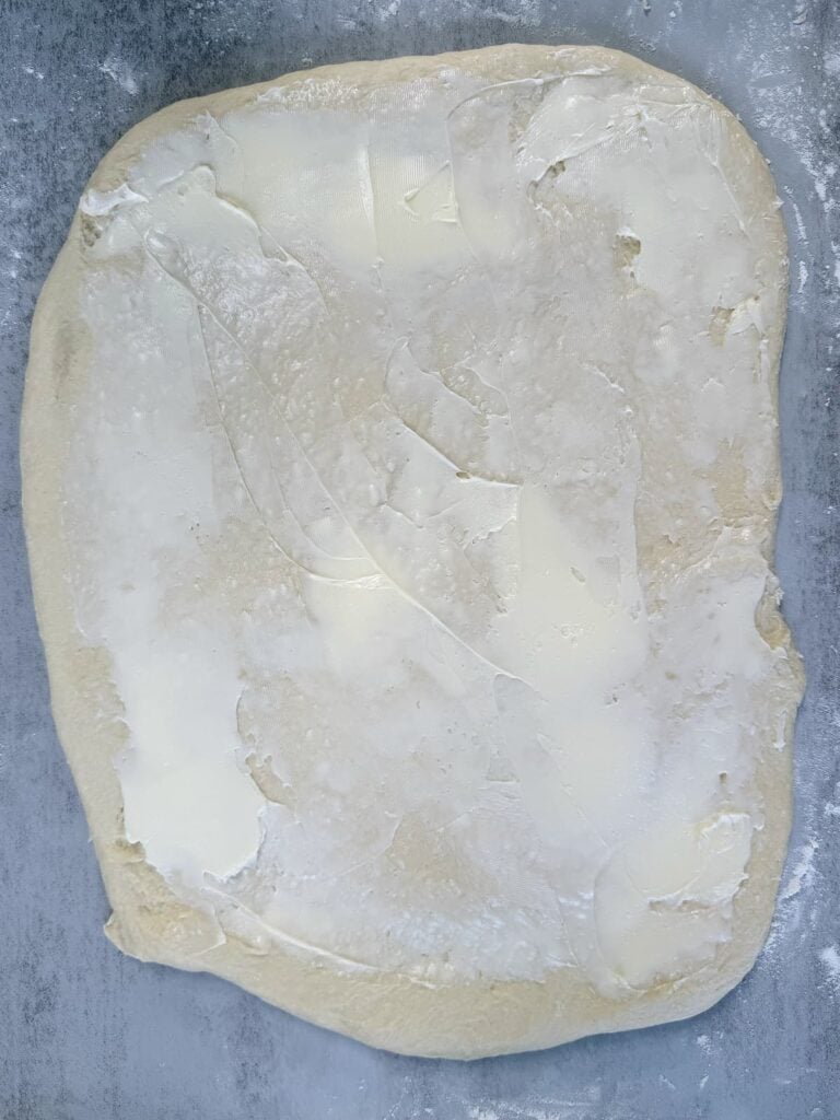 Cinnamon roll dough rolled into a rectangle with a layer of butter.