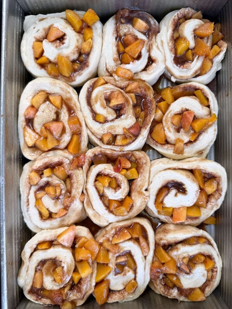 Sourdough peach cobbler cinnamon rolls added to a 9x13 pan before the first rise.