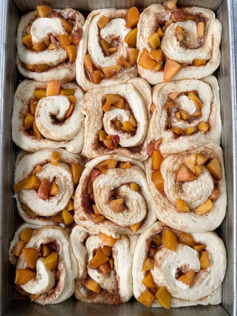 Sourdough peach cobbler cinnamon rolls in a 9x13 pan after second rise.