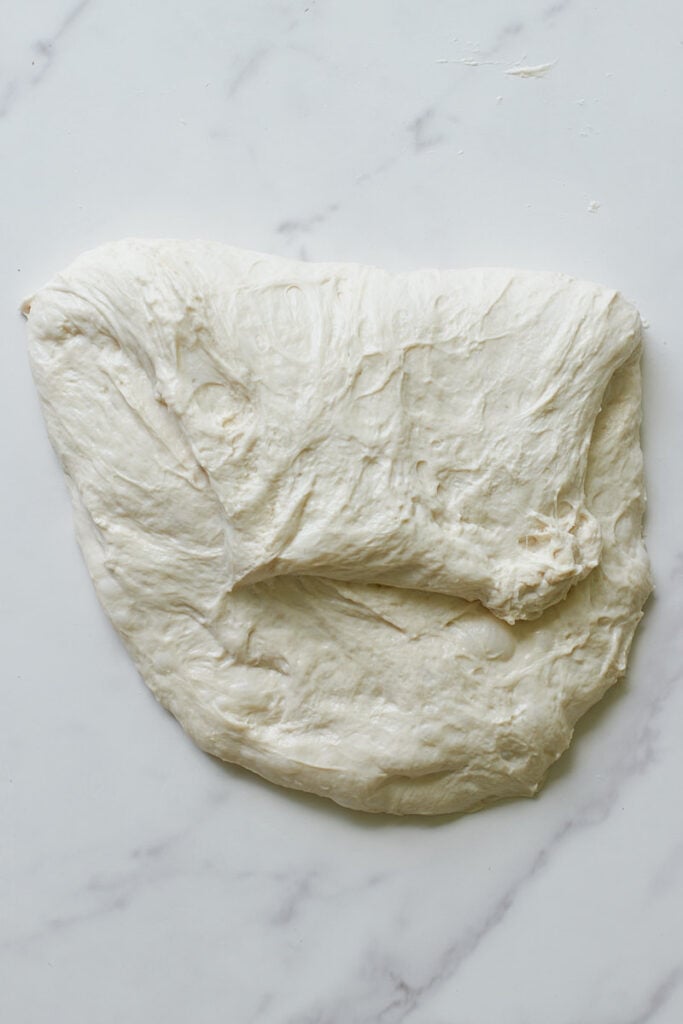 One side of sourdough bread dough folded over itself for shaping.
