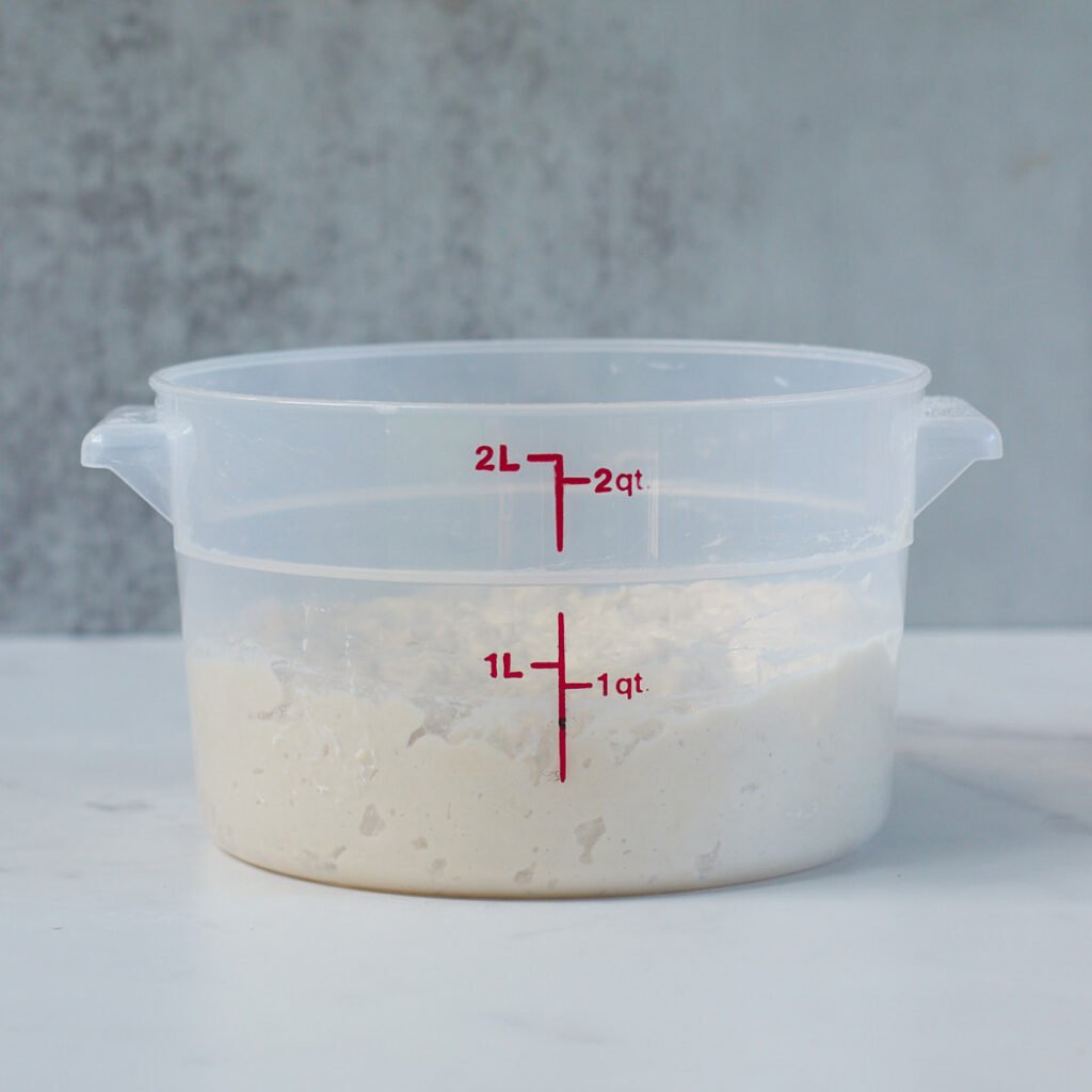 Ingredients for sourdough bread dough mixed together in 2 quart container.