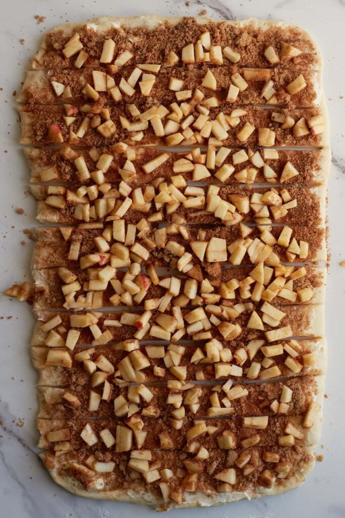 12 strips cut into dough of Apple Crisp Sourdough Cinnamon Rolls.