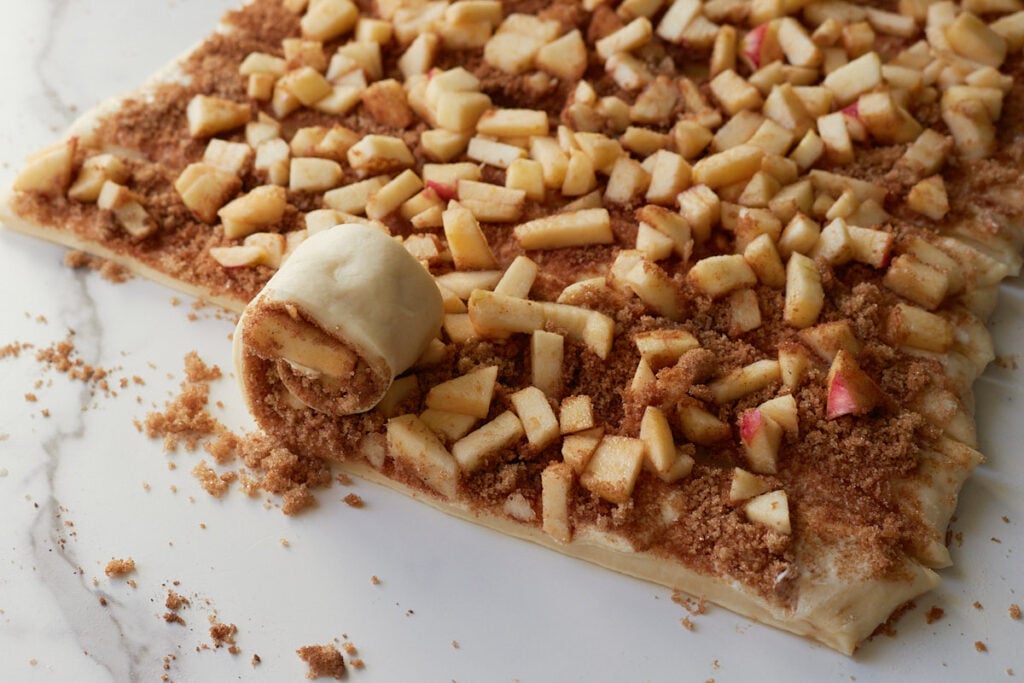 Rolling up one strip of dough for Apple Crisp Sourdough Cinnamon Rolls.