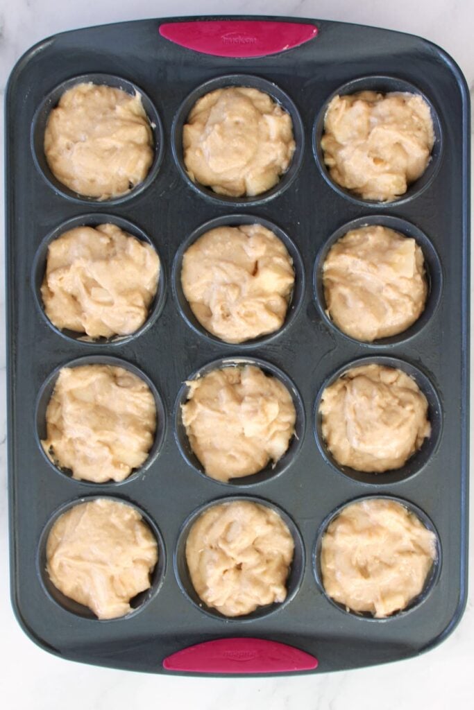 Sourdough apple muffin batter added to a muffin pan.