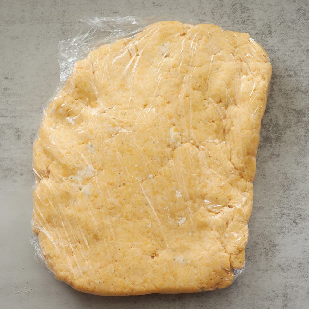 Sourdough Cheez-it dough wrapped in plastic wrap.