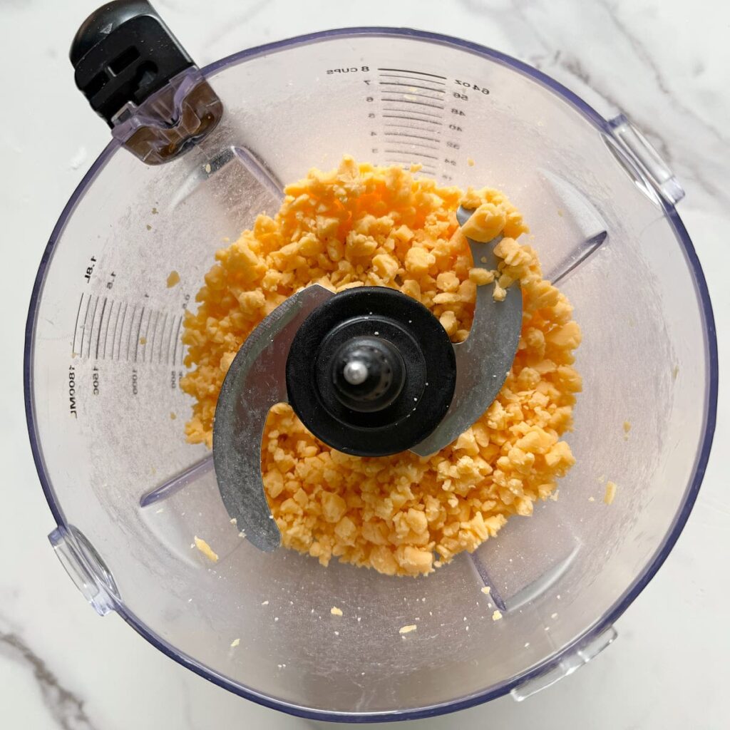 Cheese cut up in a food processor for sourdough goldfish dough.