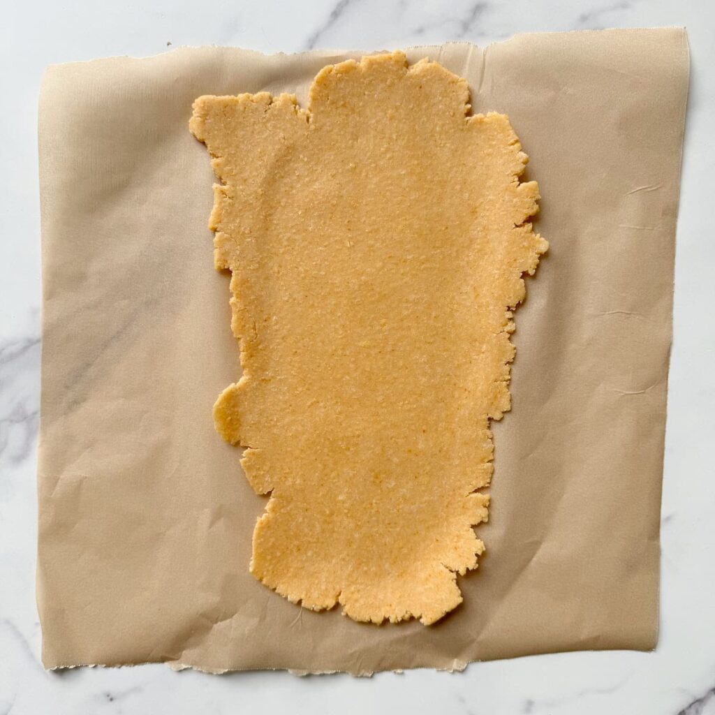 Dough for sourdough goldfish rolled out on parchment paper.