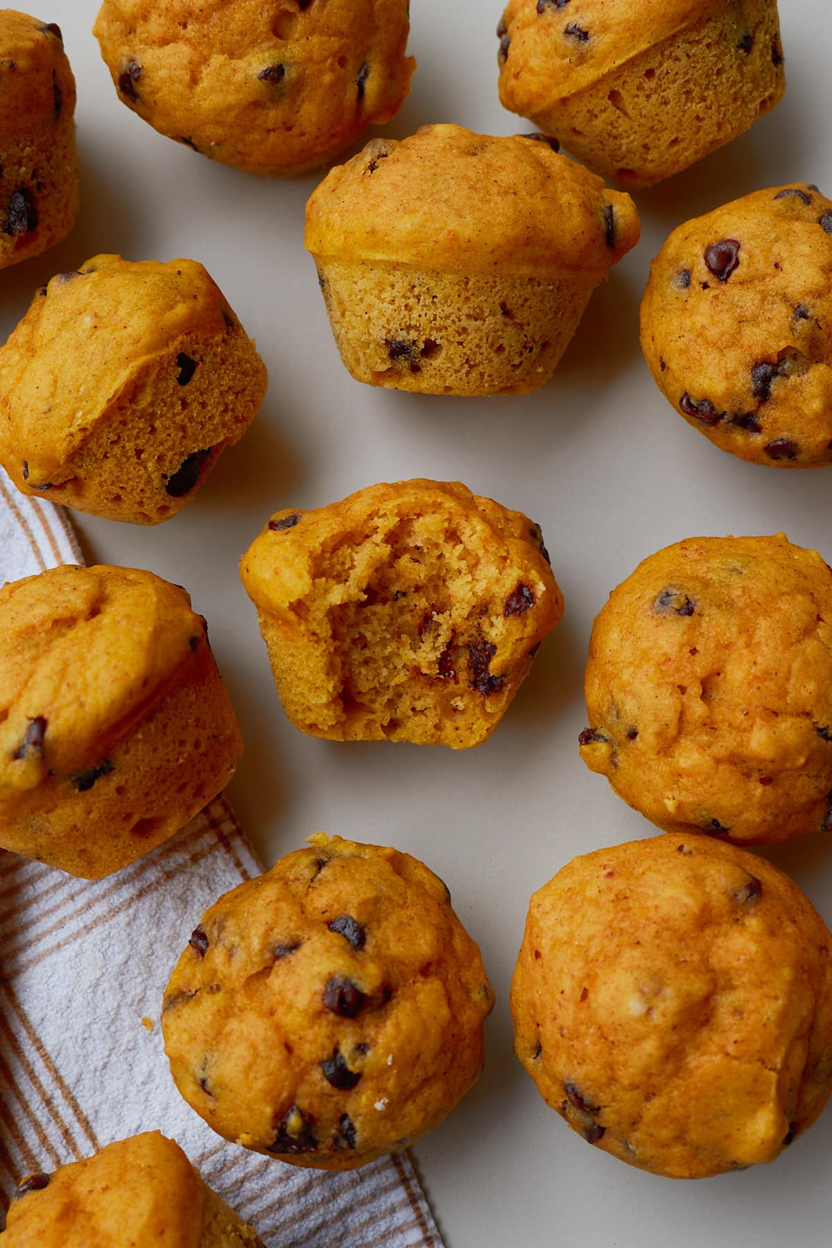 Sourdough pumpkin mini muffins with one bite taken out of a muffin.