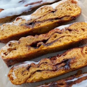 Slices of Sourdough Pumpkin Focaccia with icing on brown parchment paper.