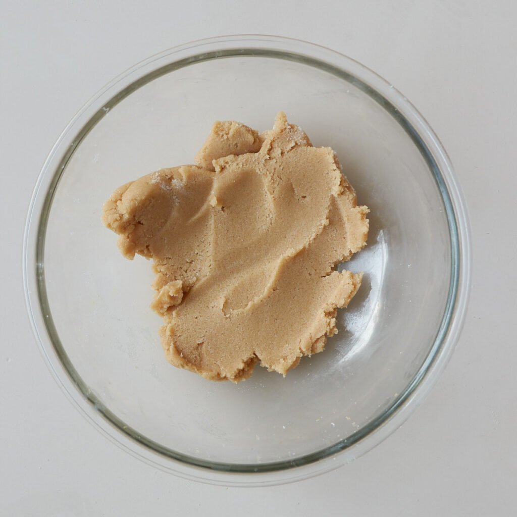 Sugar and butter creamed together to make sourdough apple muffins in a clear bowl.