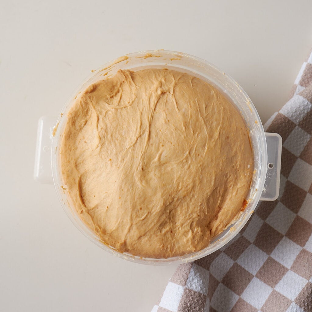 Dough for Sourdough Pumpkin Focaccia after 2nd rise in a clear straight edged container.