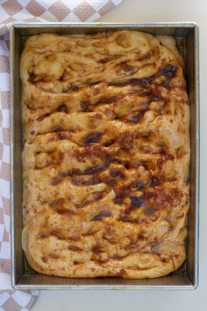 Sourdough Pumpkin Focaccia dough after second rise in 9x13 pan with dimples in the dough.