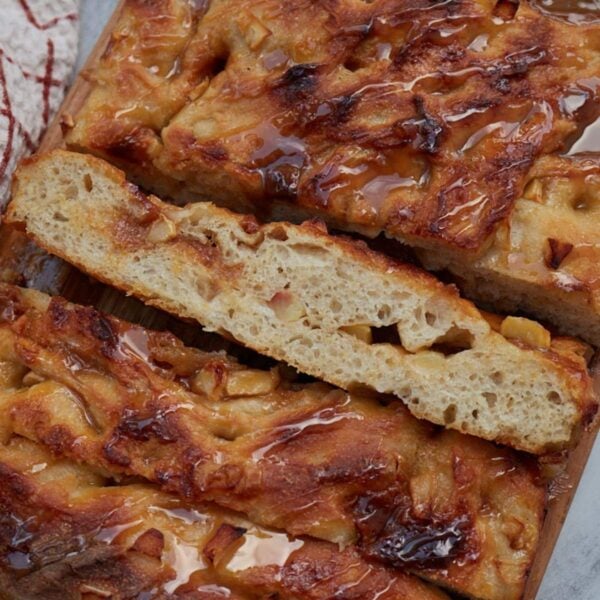 Slices of Caramel Apple Sourdough Focaccia on a wooden board next to a white and red towel.