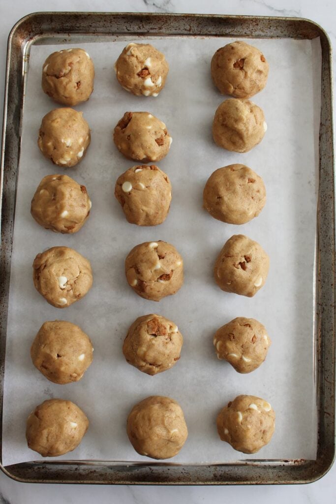 18 Cookie butter sourdough cookie dough balls on a parchment lined sheet pan.