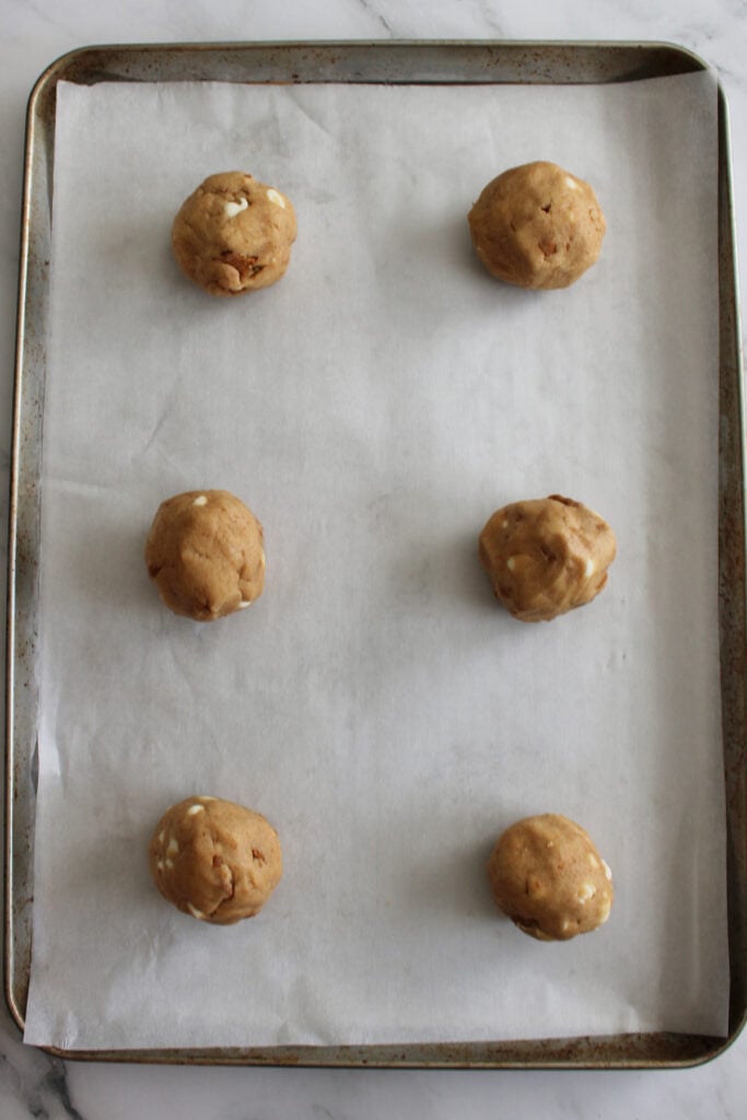 6 dough balls for cookie butter sourdough cookies on a parchment lined sheet pan.